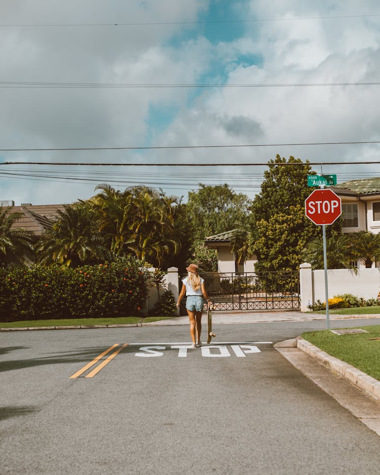 Woman Walking Down The Street With A Skateboard