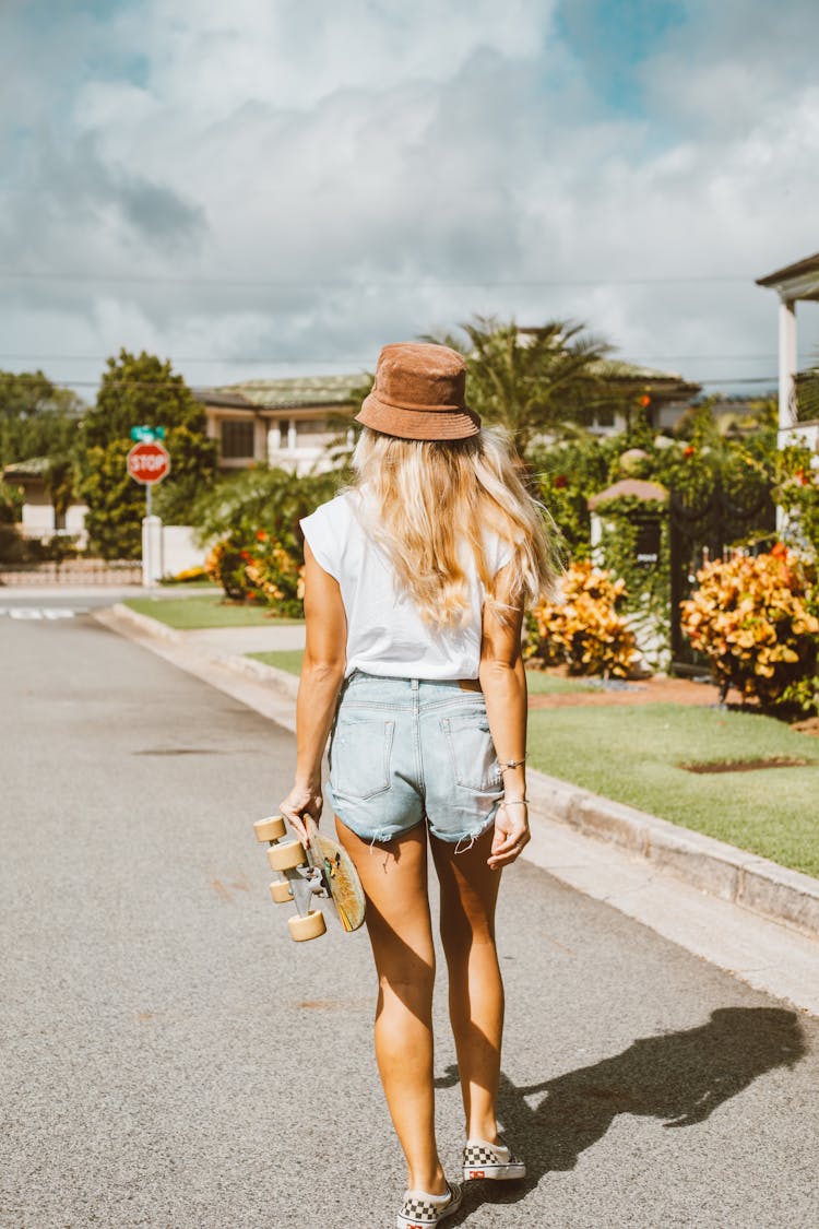 Back View Of A Woman Holding A Skateboard