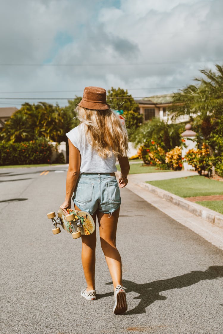 Woman Holding A Skateboard Walking Down The Street