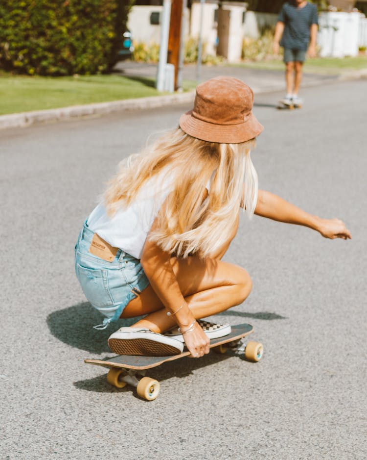 Blonde Woman With Hat Skateboarding On Street