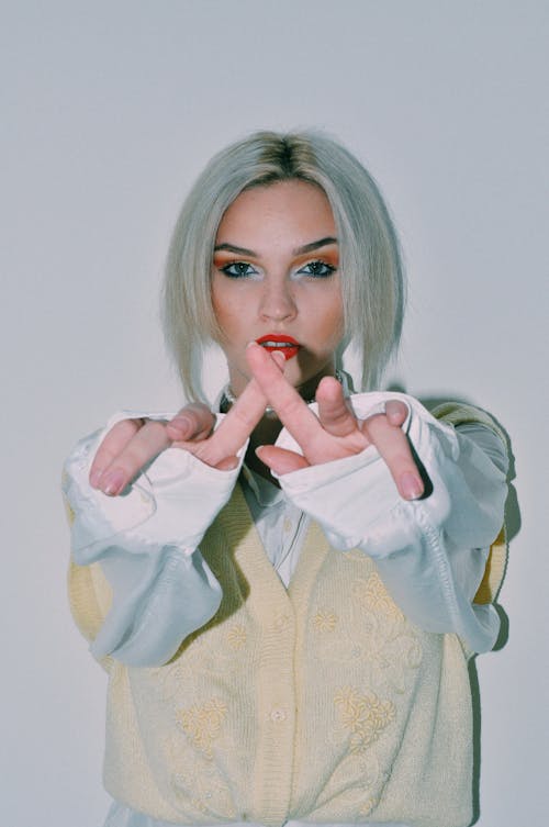 Stylish young woman gesturing against white wall