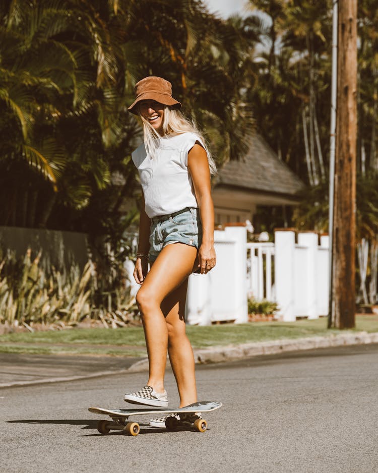 Smiling Woman Skateboarding On The Street In Summer