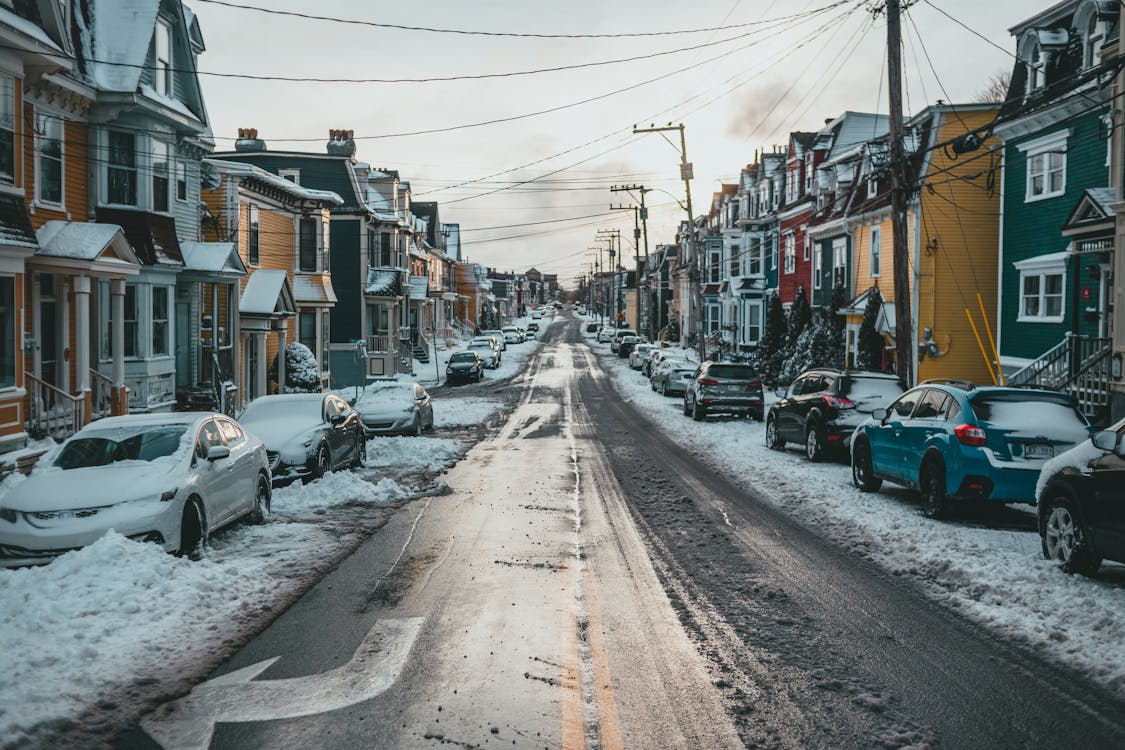 Straight road between residential houses and cars in winter town
