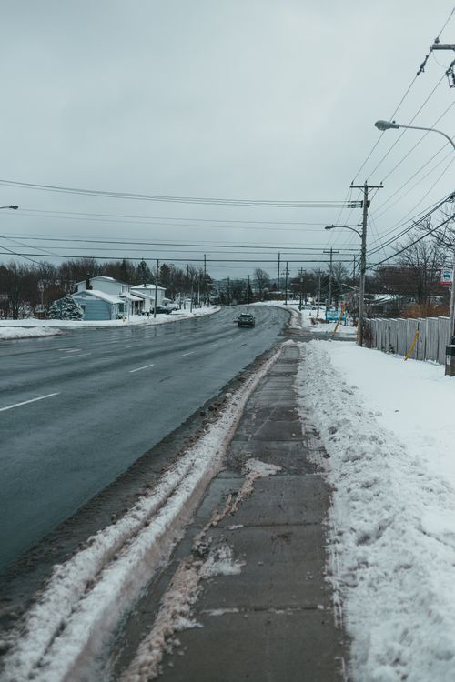 Free Transport driving on asphalt roadway between houses and snowy pavement under lamp posts in wintertime Stock Photo