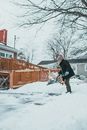 Woman removing snow from pavement in winter town