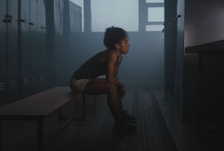 Athlete resting on a bench in a dim training room — Tima Miroshnichenko on Pexels