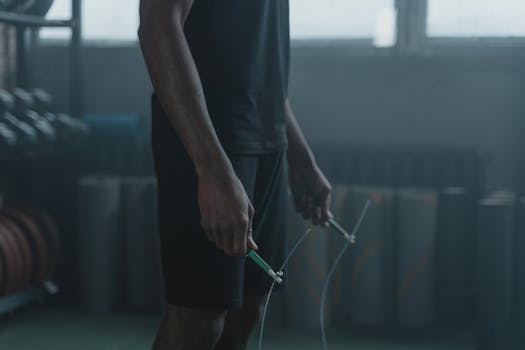Athlete preparing for a jump rope workout in a dimly lit modern gym.