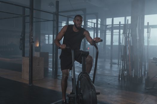 Focused man in gym working out on elliptical machine, promoting fitness and lifestyle.