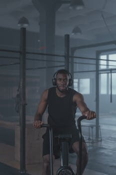 Man working out on a stationary bike in a gym, focused and determined.