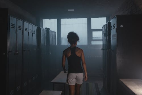 A Woman Walking Near Metal Lockers