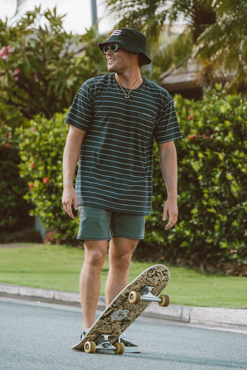 Photo of a Man in a Bucket Hat Standing Near His Skateboard
