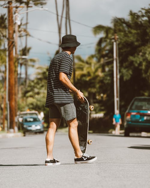Selective Focus Photo of a Skater in a Bucket Hat Crossing a Road
