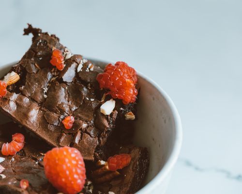 Free Close-up of a chocolate brownie topped with fresh raspberries in a bowl. Stock Photo