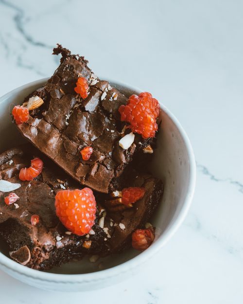 Free Close-up of chocolate brownies topped with fresh raspberries in a bowl. Stock Photo