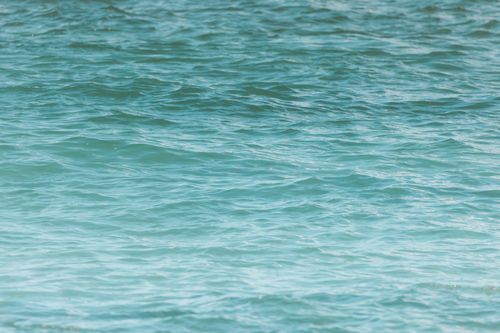 Free A serene view of turquoise ocean waves glistening under the sunlight. Stock Photo