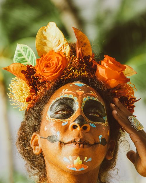 Free Close-up portrait of a woman with Day of the Dead face paint and floral headdress outdoors. Stock Photo