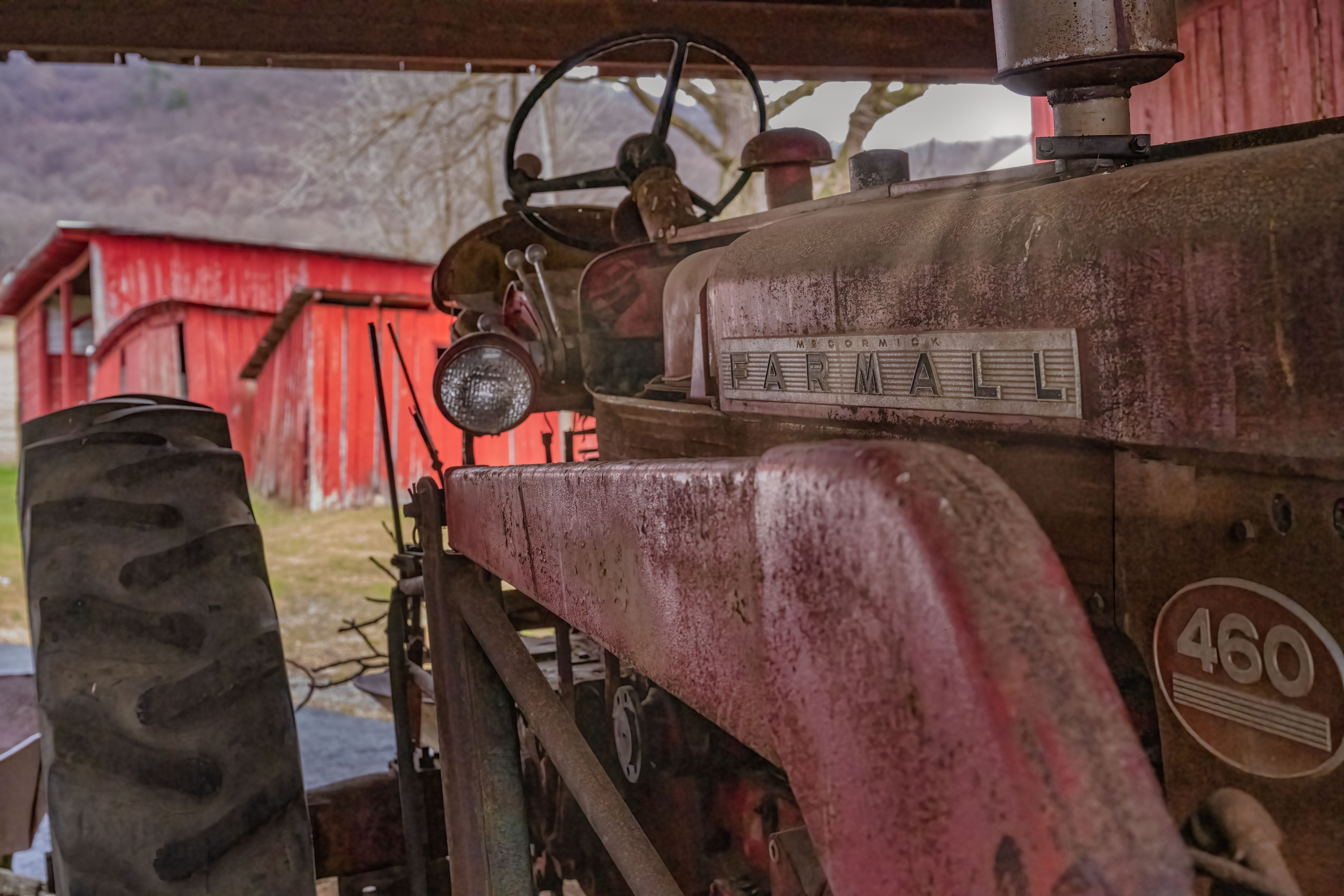 Non-running farm tractor and rusted box truck parked behind an Arkansas barn, scheduled for free removal