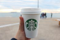 在海边，一只手拿着星巴克咖啡杯，捕捉一个宁静的户外时刻