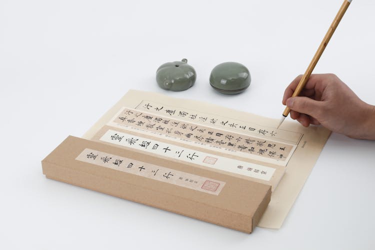 Person Writing Chinese Letters On A Letter Paper Sheet