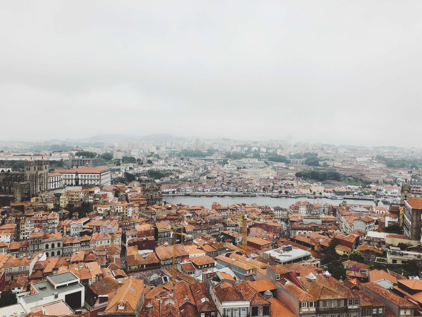 Aerial view capturing Porto's historic rooftops and Douro River under a misty sky.