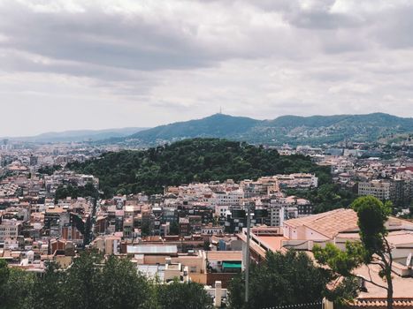 Explore the stunning panoramic view of Barcelona's vibrant cityscape with lush greenery and distant mountains.