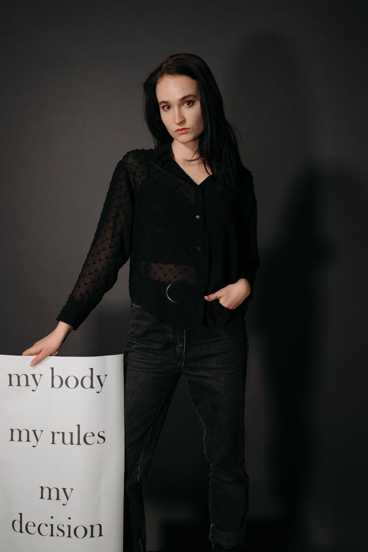 A Woman In Black Long Sleeves Holding A Poster