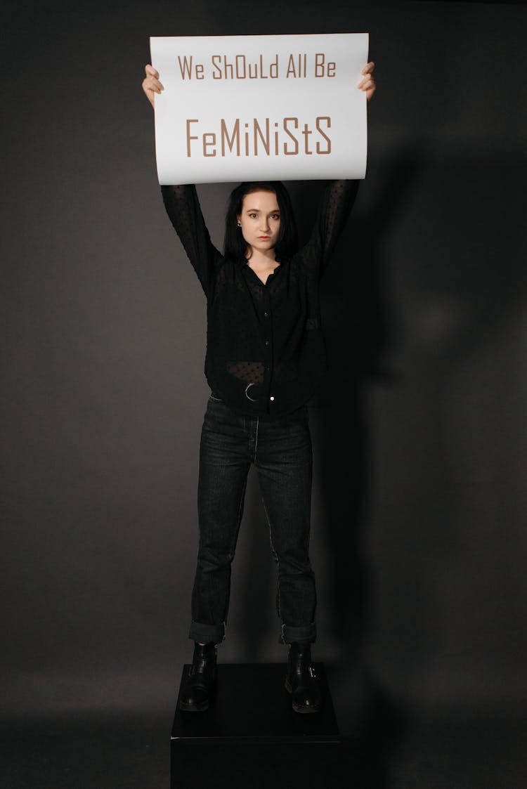 A Woman Raising Her Hands While Holding A Poster