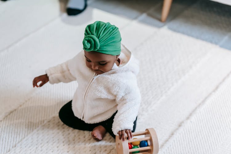 Curious Little Infant Girl Playing With Wooden Toy At Home