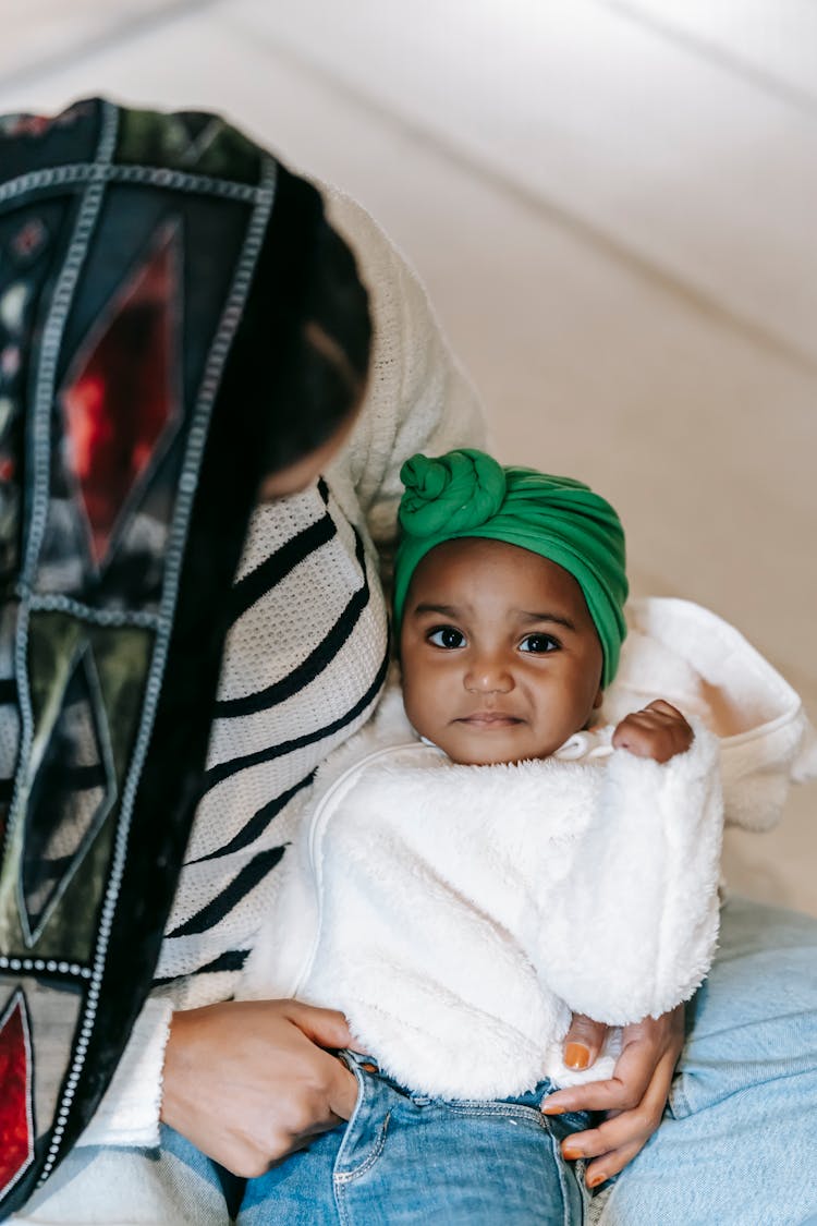 Adorable Little Indian Baby Girl Sitting On Mother Knees