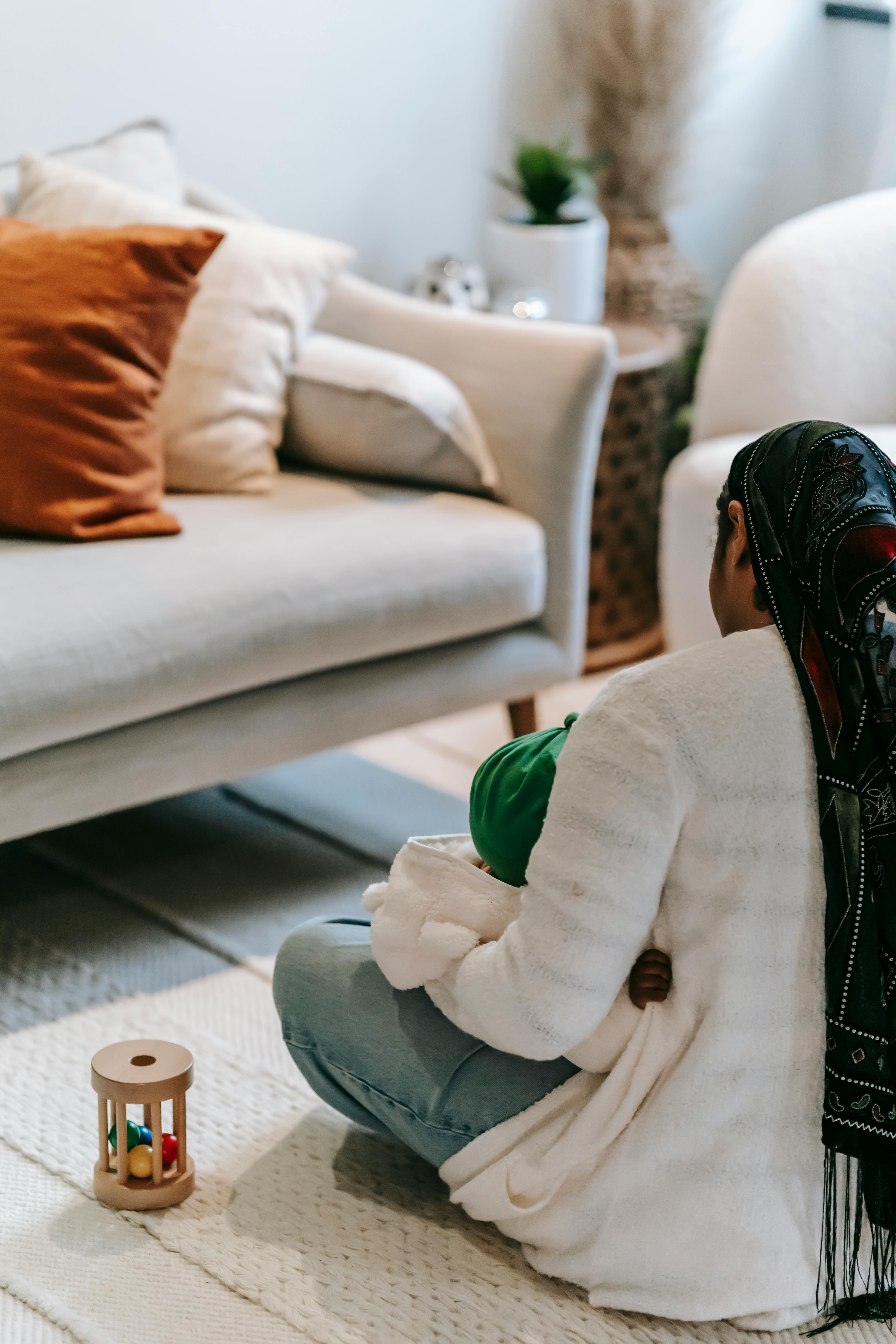 black woman in headscarf sitting on floor with child on knees