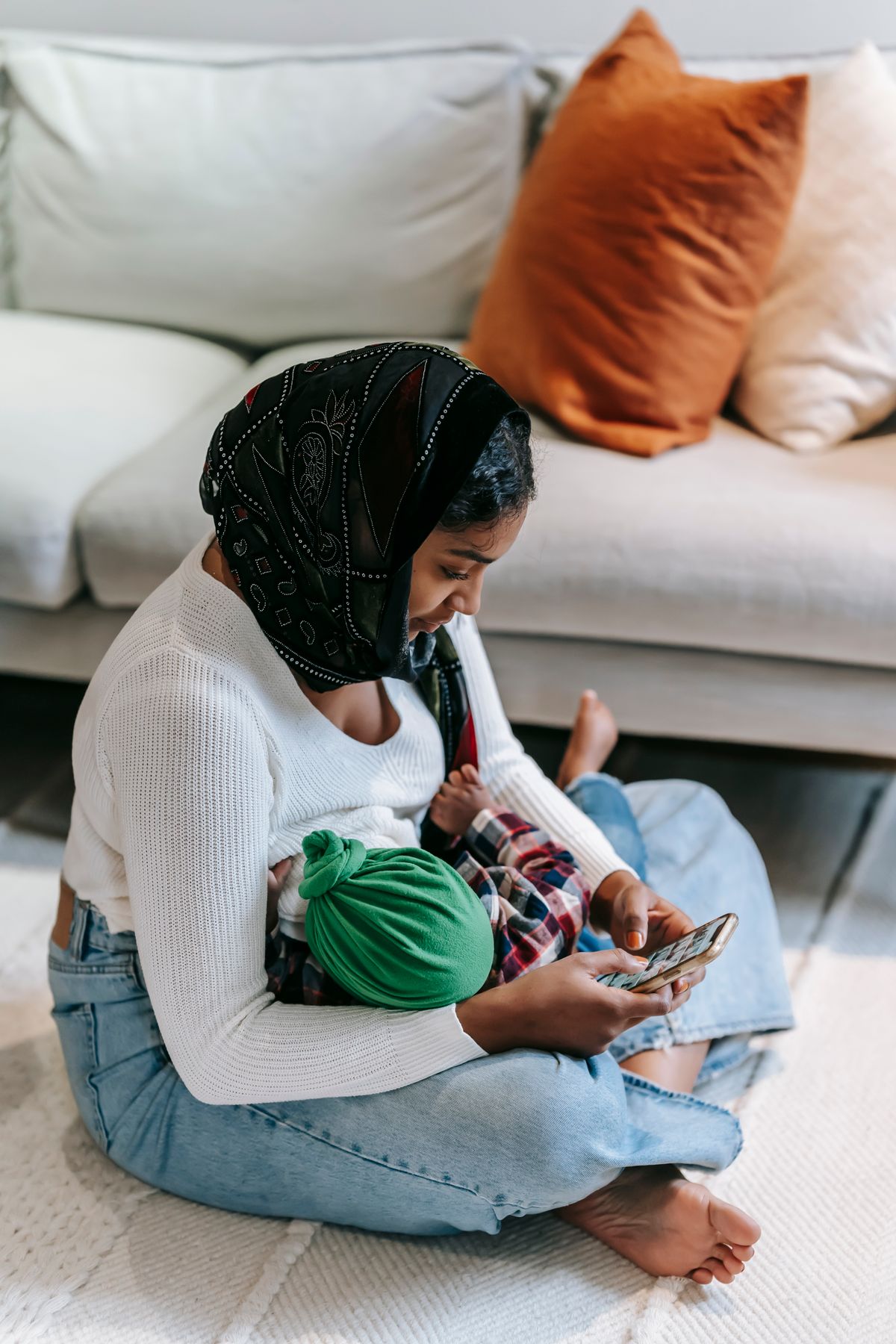 Ibu bertudung mendukung bayi baru lahir sambil merancang majlis aqiqah