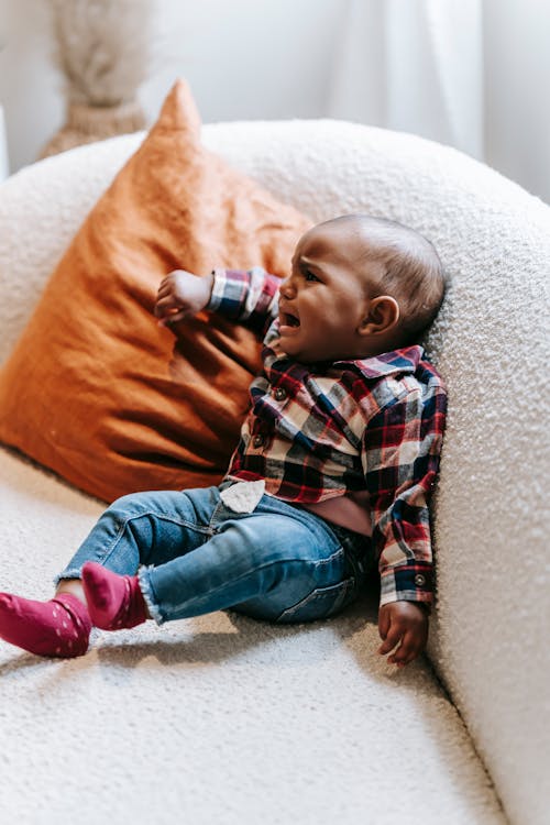 Upset ethnic baby crying on couch