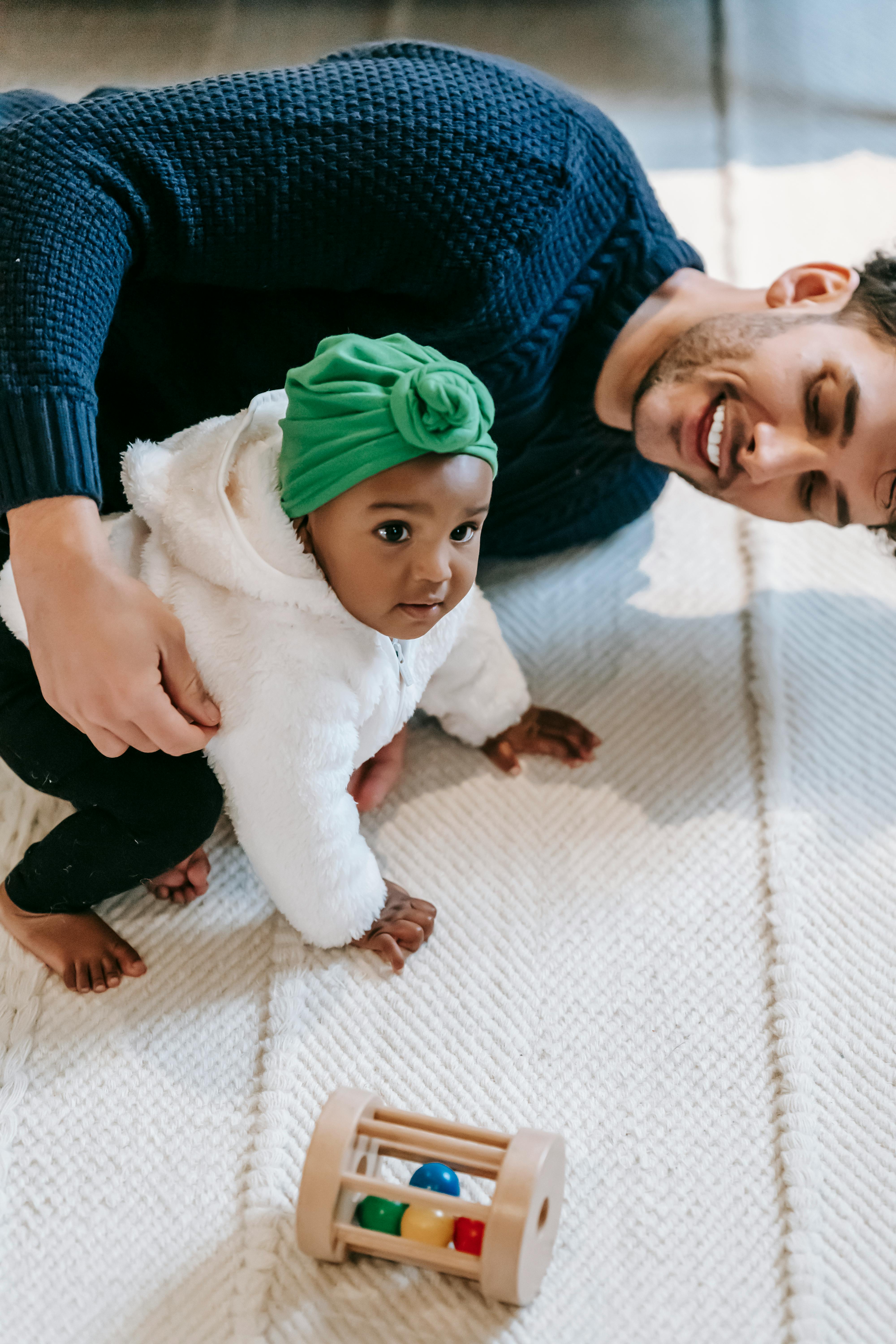 Happy multiethnic father and baby playing together on carpet at home