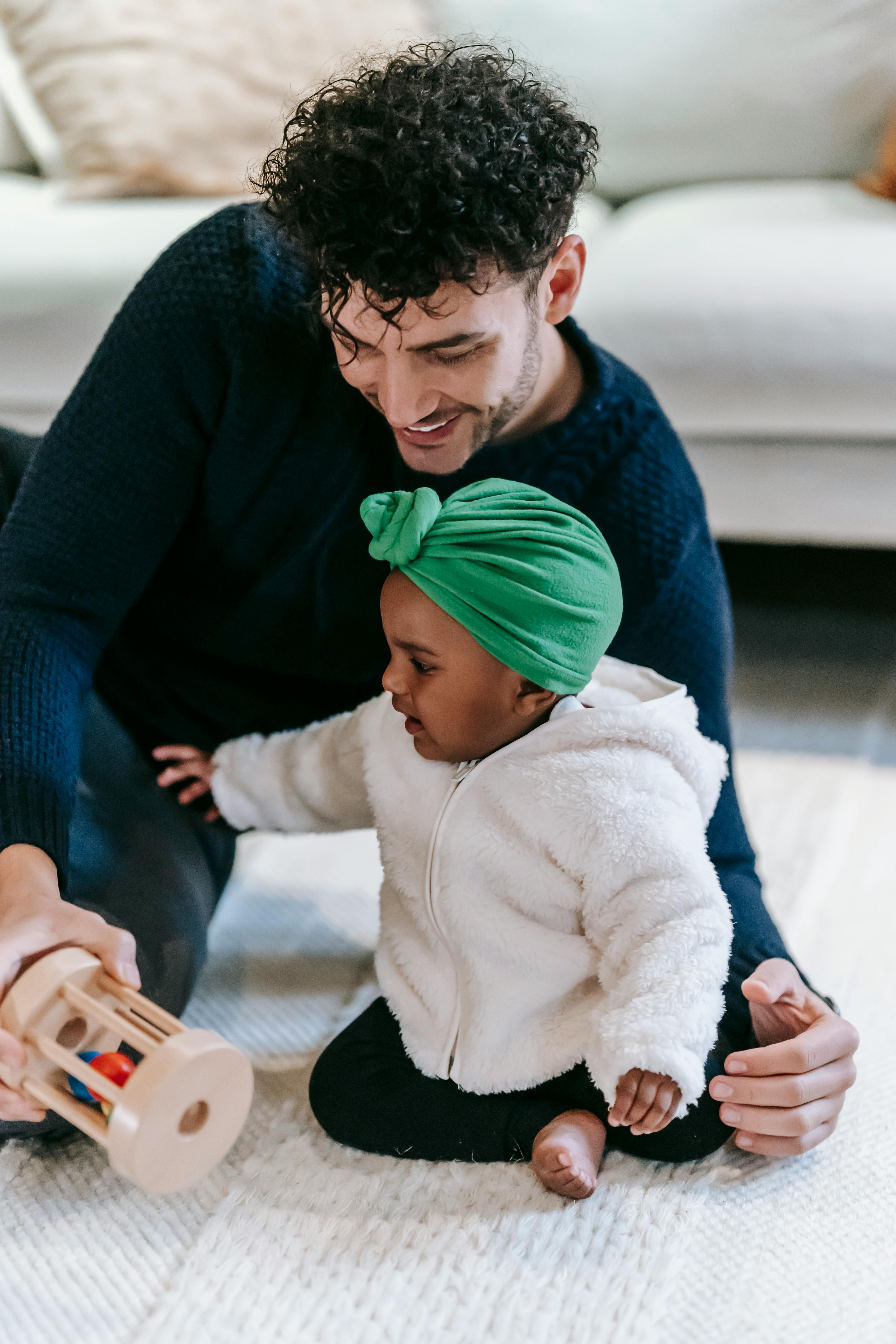 adorable indian baby playing on floor with positive ethnic father