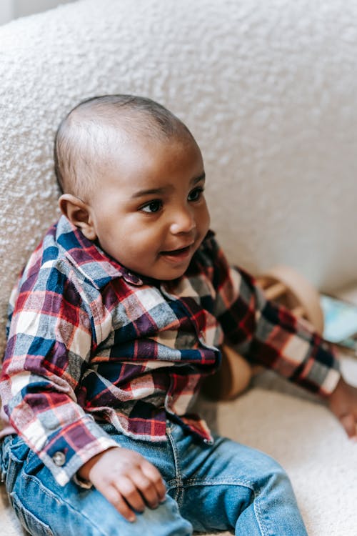 Adorable ethnic toddler smiling on soft sofa
