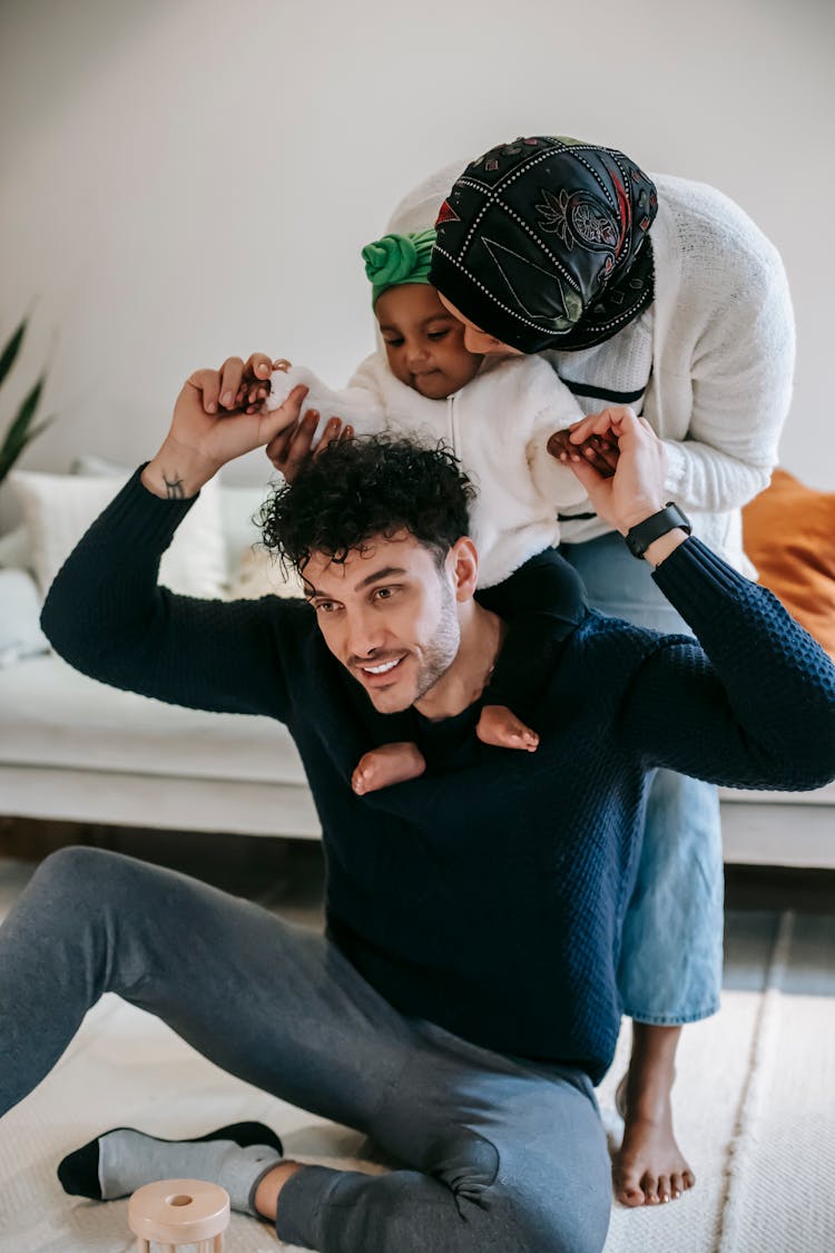 Smiling Father Holding Hands Of Daughter On Shoulders With Mother