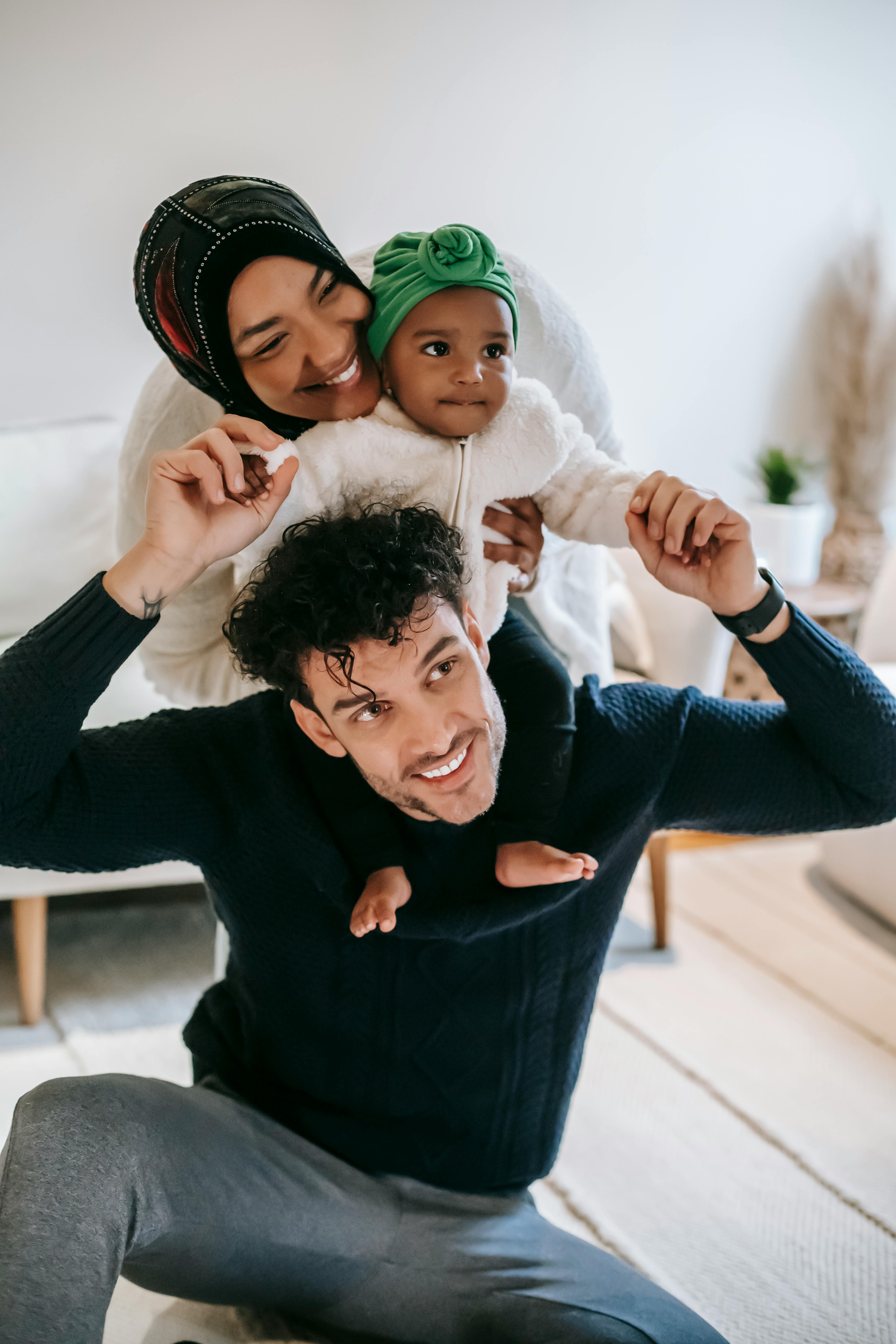 happy muslim mother embracing black baby sitting on father