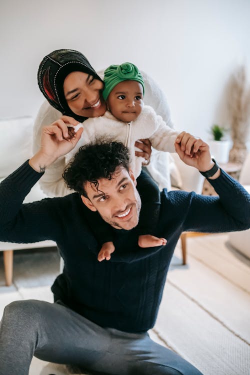 Free Happy Muslim mother embracing black baby sitting on father Stock Photo