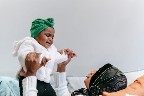 Black mother comforting capricious baby on couch