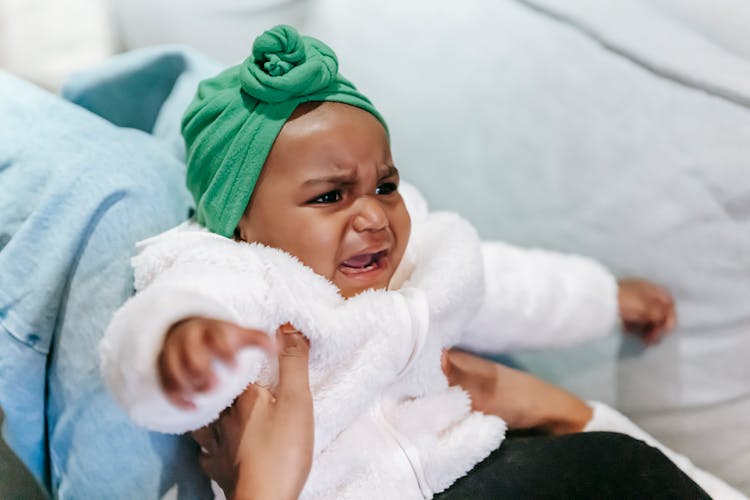 Crying Black Baby In Turban In Mother Hands