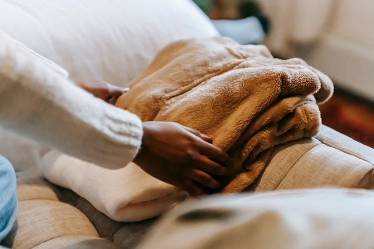 Black Woman Stacking Clothes On Sofa