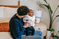Father embracing adorable black baby in bedroom