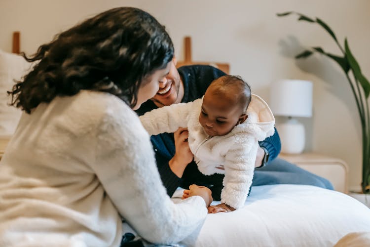 Positive Diverse Family Playing With Newborn Baby