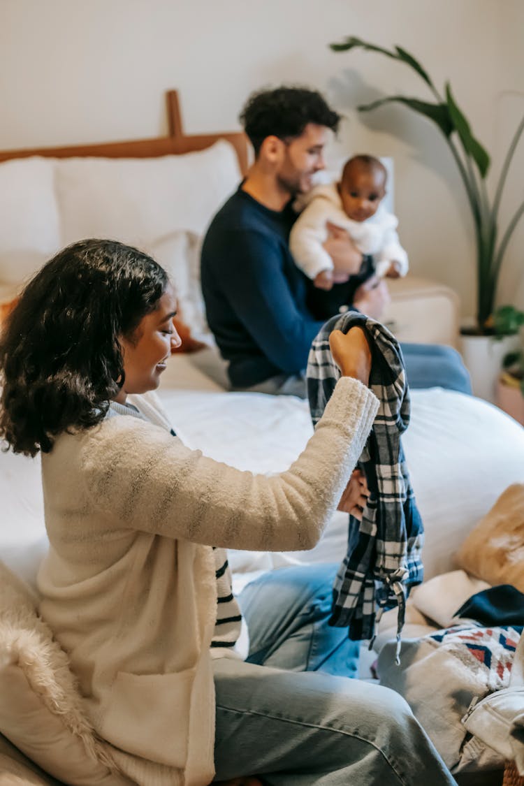 Black Woman With Clothes Sitting Near Ethnic Father With Baby