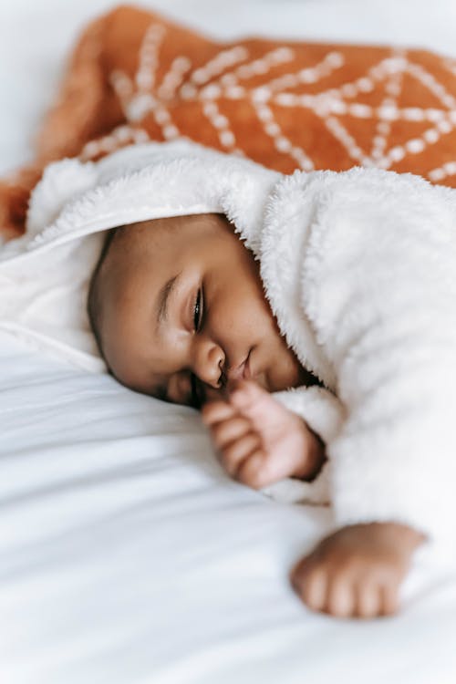 Free Sleeping black infant baby on bed Stock Photo