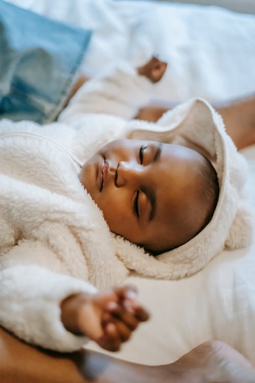 Adorable black infant baby sleeping on bed