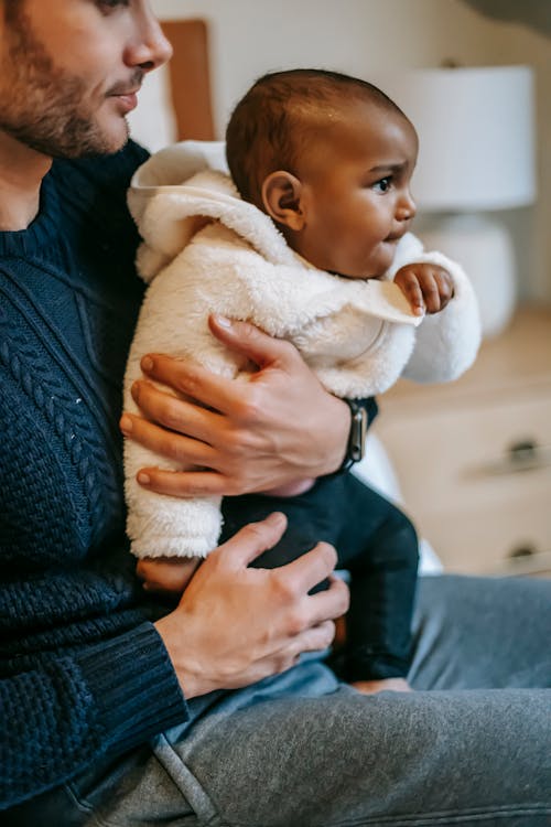 Crop ethnic father hugging black infant baby