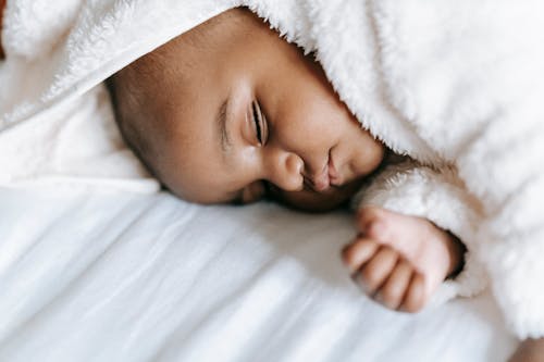 Sleeping newborn black baby lying on bed