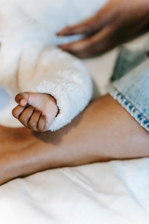 Free Hand of crop black infant on leg of anonymous African American mother Stock Photo