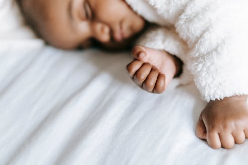 Adorable ethnic infant sleeping on bed